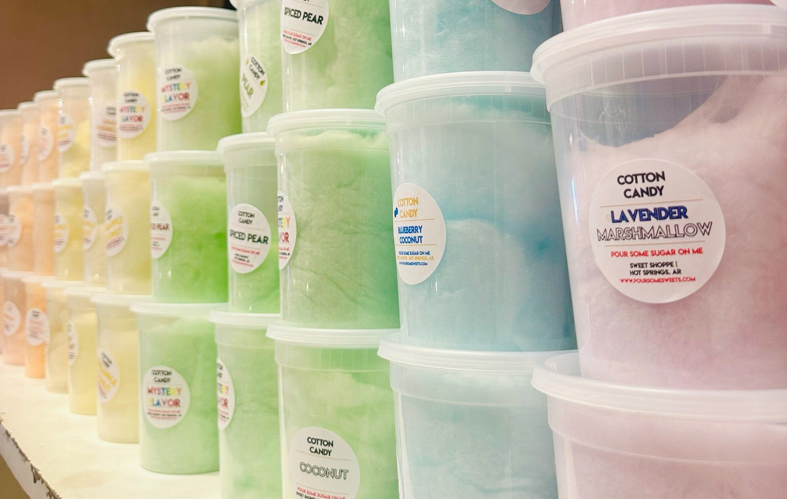 Row of colorful cotton candy containers on a shelf.